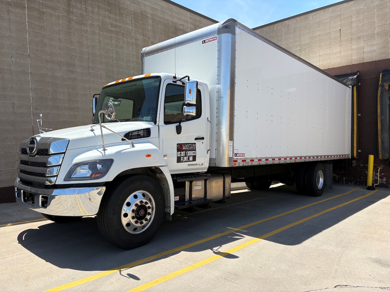 Quantum industrial white delivery truck backed up to the loading bay.